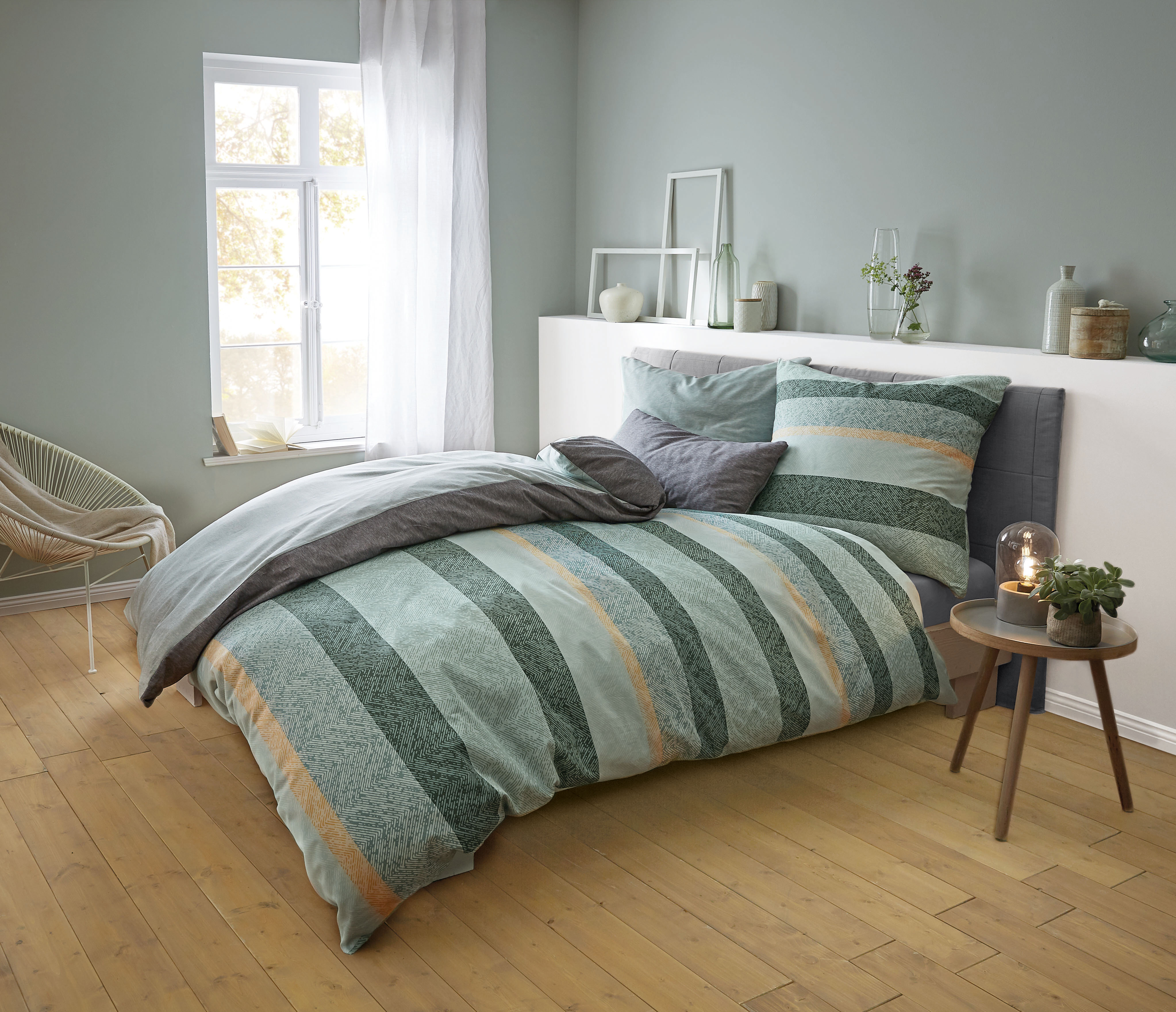Bettwäsche-Set in Grün- und Grautönen mit Streifenmuster, gemütlich arrangiert in modernem Schlafzimmer mit Holzboden.