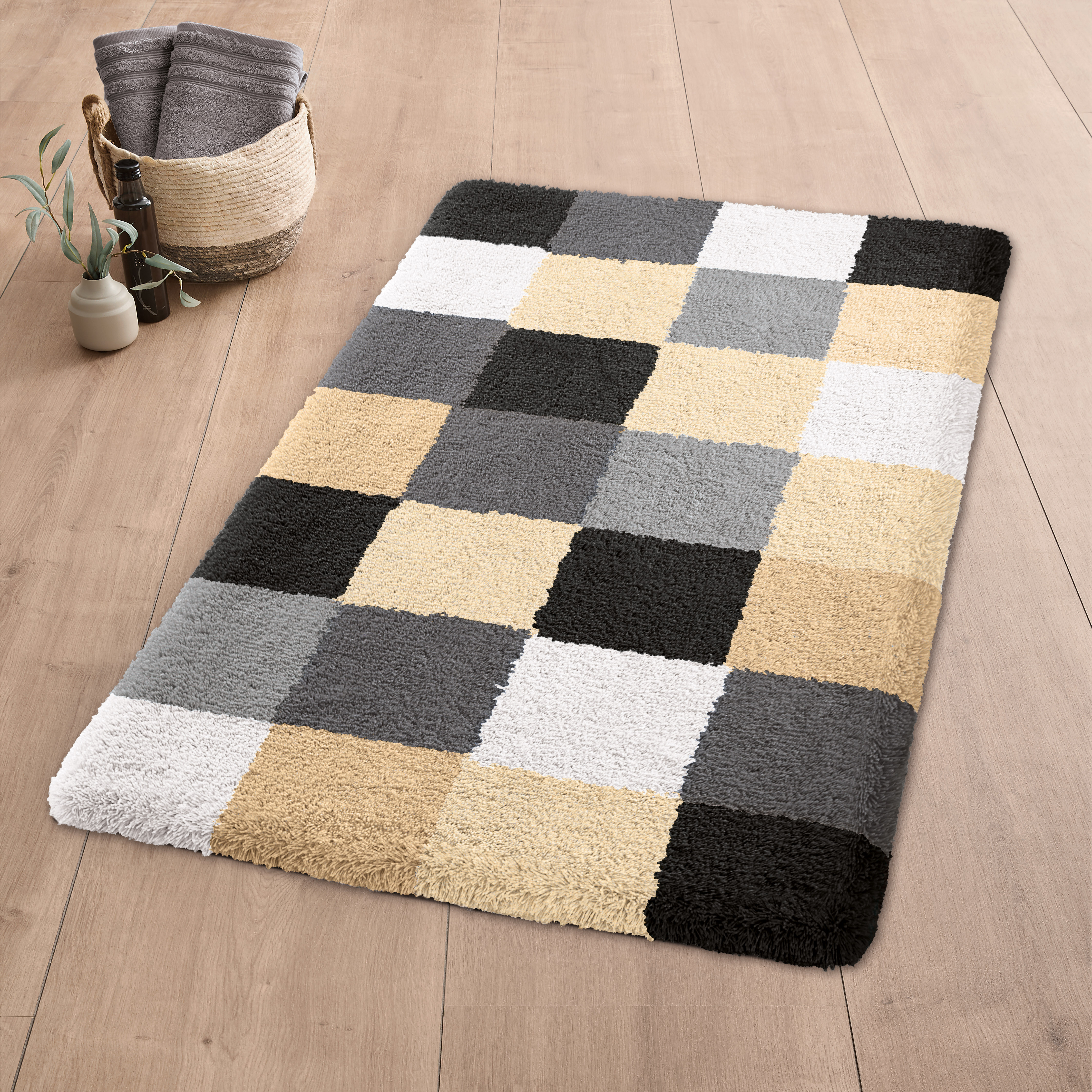 Moderner Badteppich mit Karomuster in Beige-, Grau- und Schwarztönen auf Holzfußboden, dekoriert mit Korb und Pflanze.