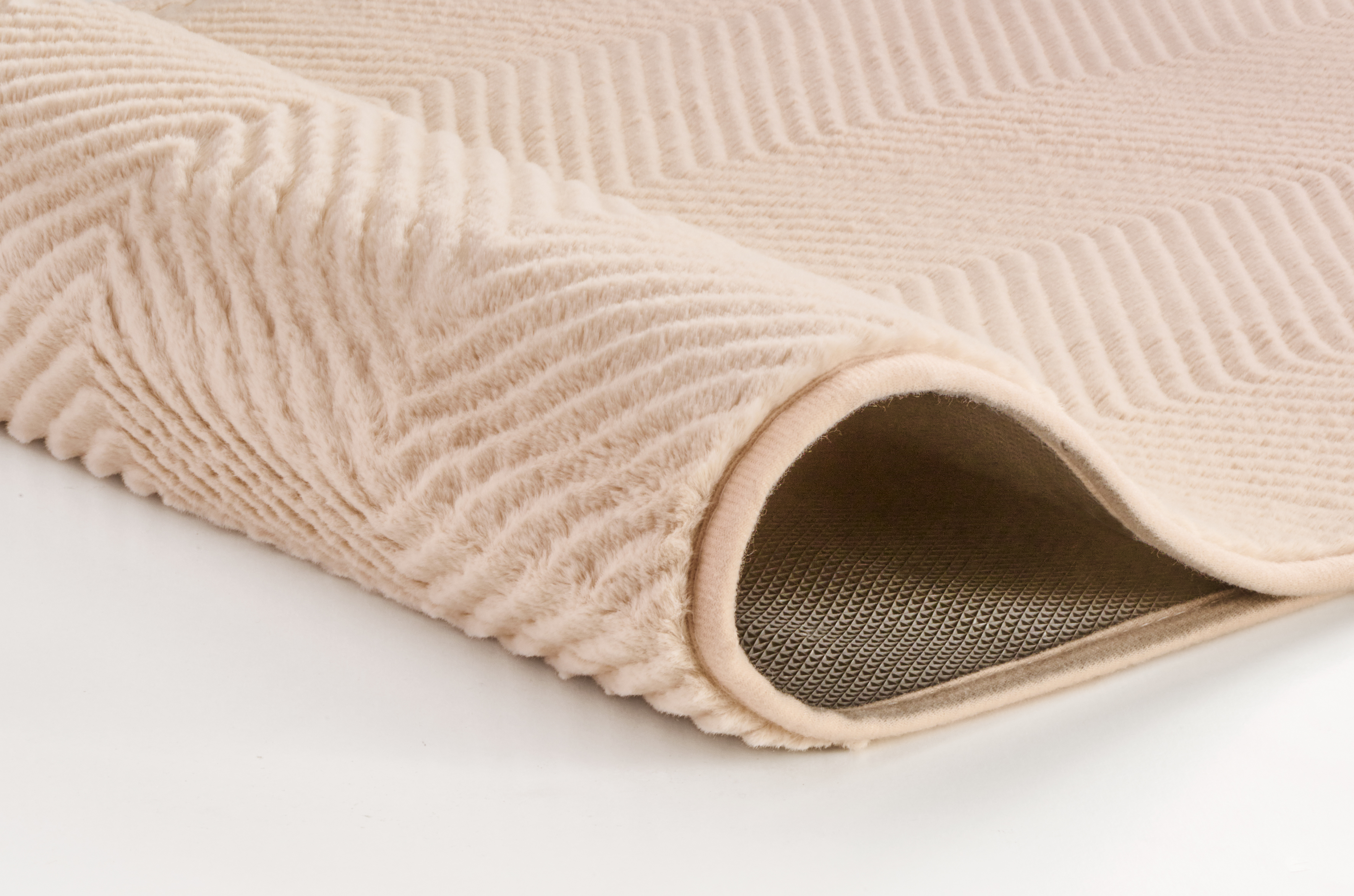 Weicher, cremefarbener Teppich mit Chevron-Muster und rutschfester Unterseite, ideal für Wohn- und Schlafzimmer.