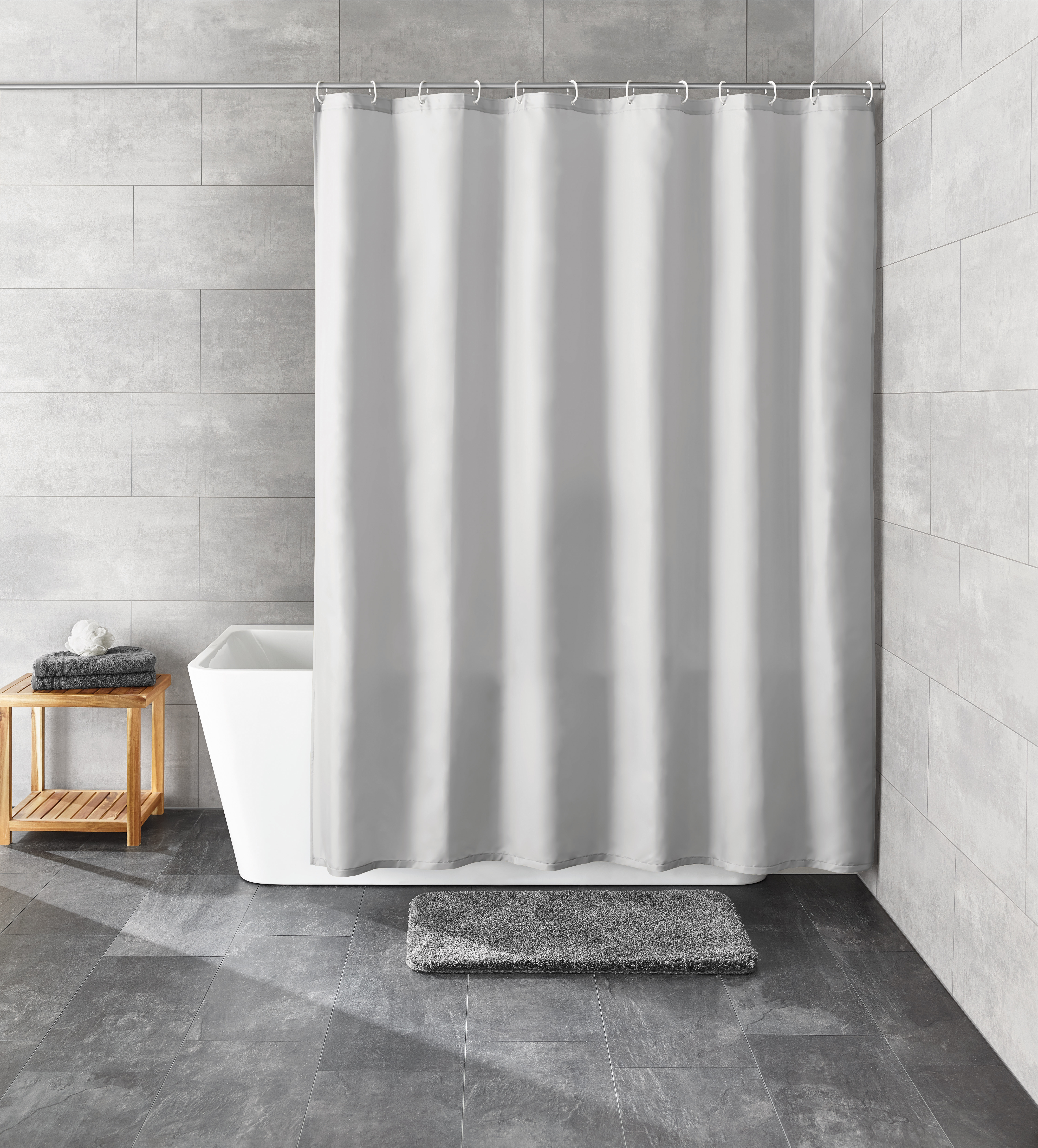 Grauer Duschvorhang in modernem Badezimmer mit grauen Fliesen, Badewanne, Holzregal und grauem Badteppich.