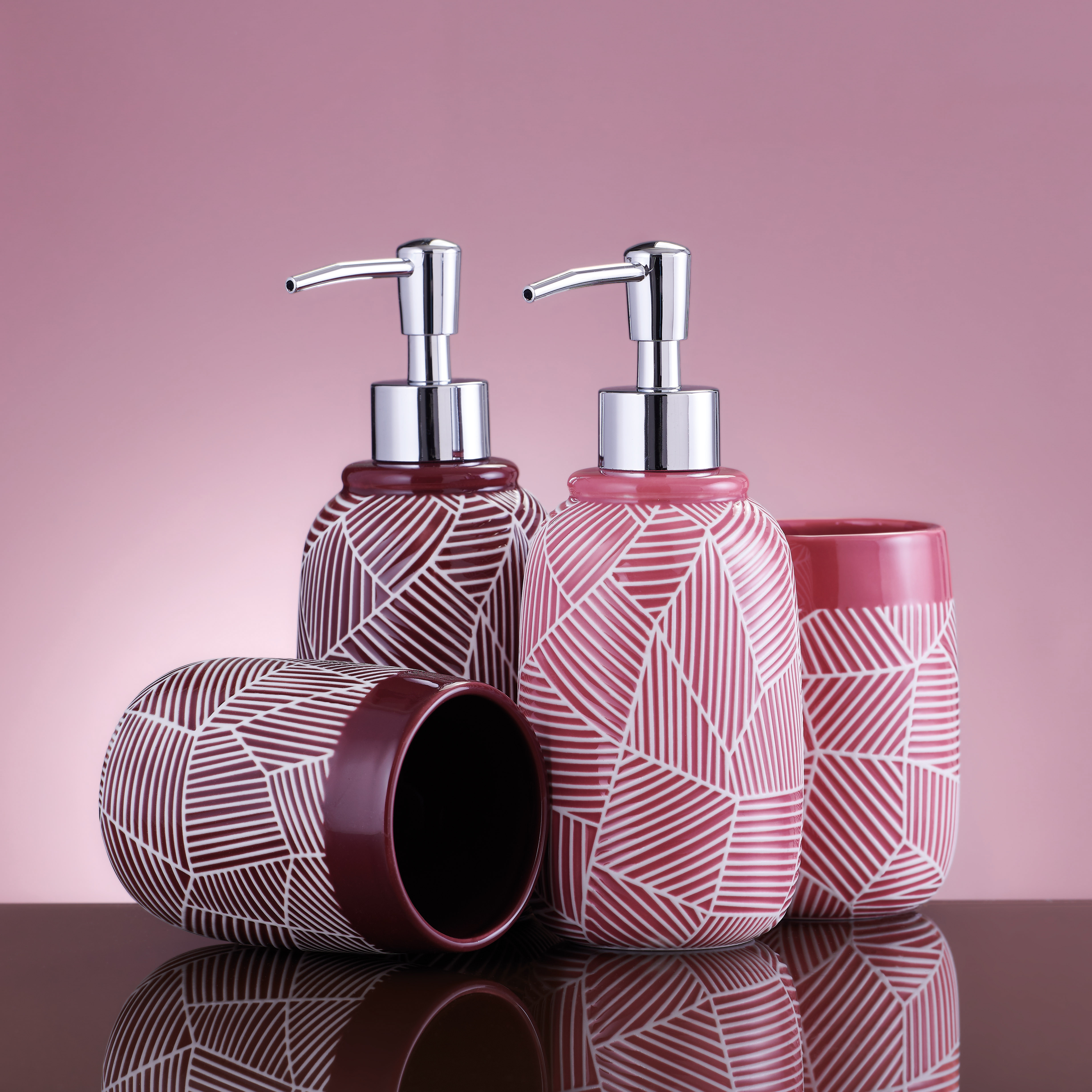 Set aus Seifenspendern und Bechern in Rosa mit geometrischem Muster, ideal für stilvolle Badezimmer.