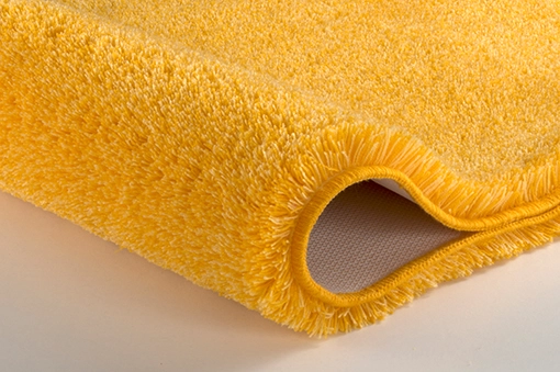 Gelber, flauschiger Badteppich mit rutschfester Unterseite, ideal für ein gemütliches und sicheres Badezimmer.