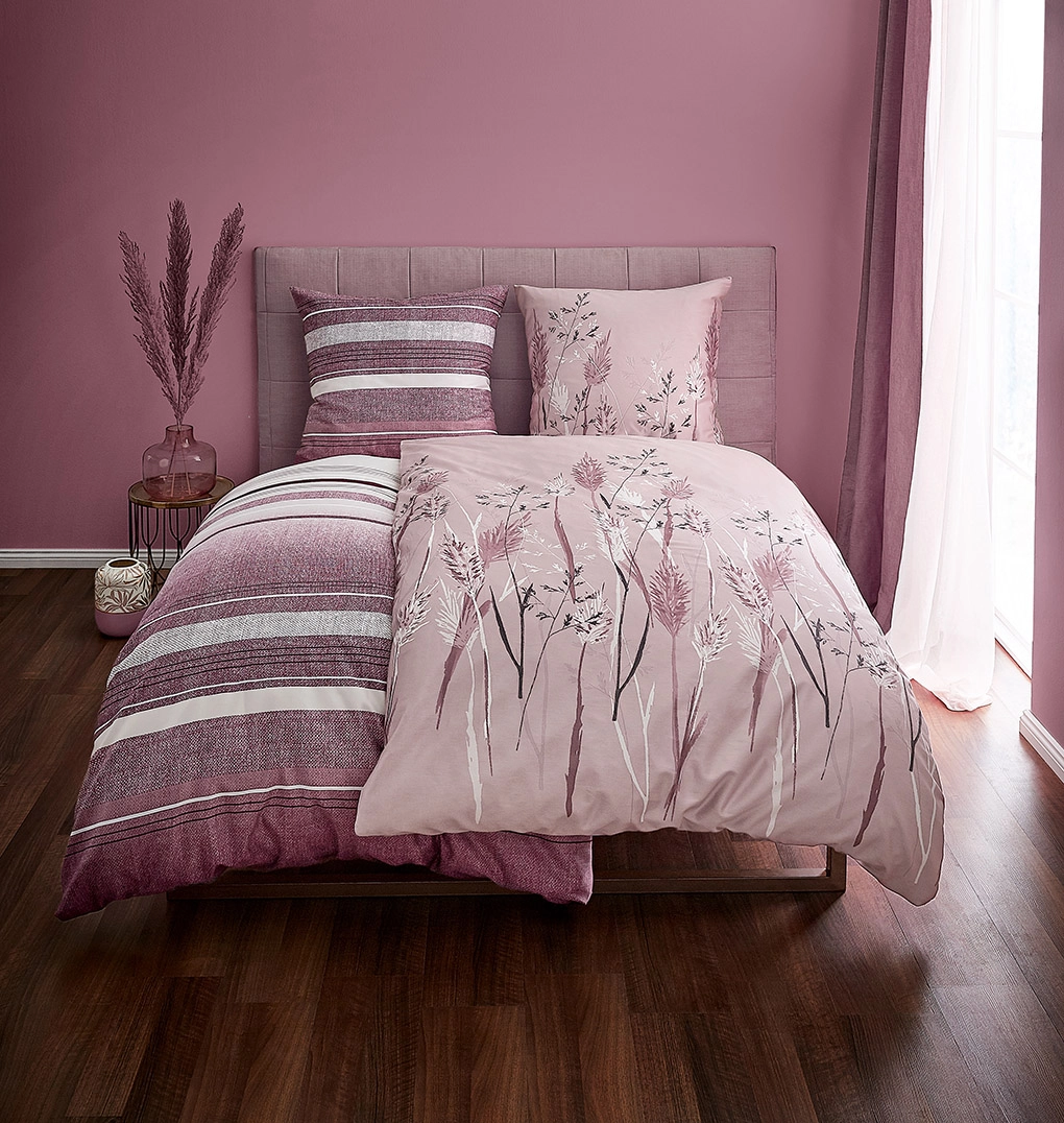 Bettwäsche-Set in Rosa mit floralen und gestreiften Mustern, dekoriert mit passenden Kissen und Vorhängen in einem stilvollen Schlafzimmer.