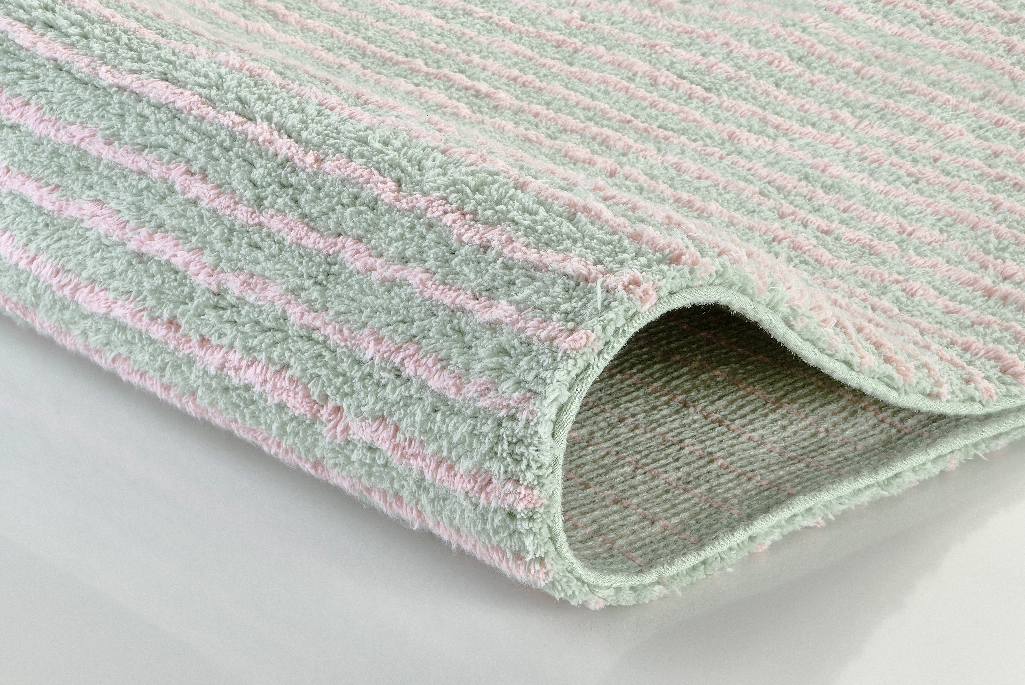 Weicher, pastellfarbener Badteppich mit Streifenmuster in Rosa und Mintgrün, ideal für ein gemütliches Badezimmer.