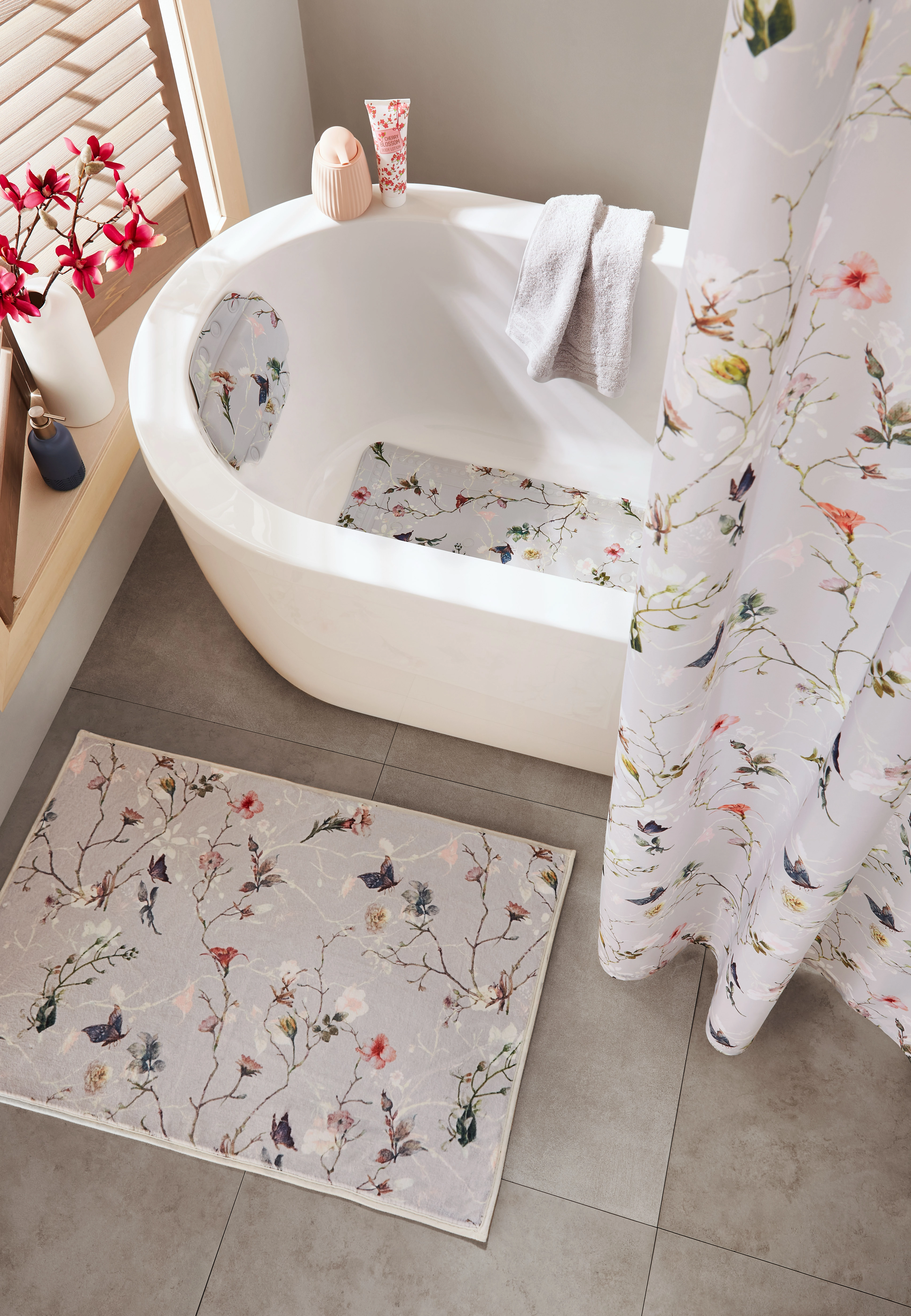 Elegantes Badezimmer-Set mit floralen Mustern, bestehend aus Duschvorhang, Badewanneinlage und Badematte in sanften Farben.