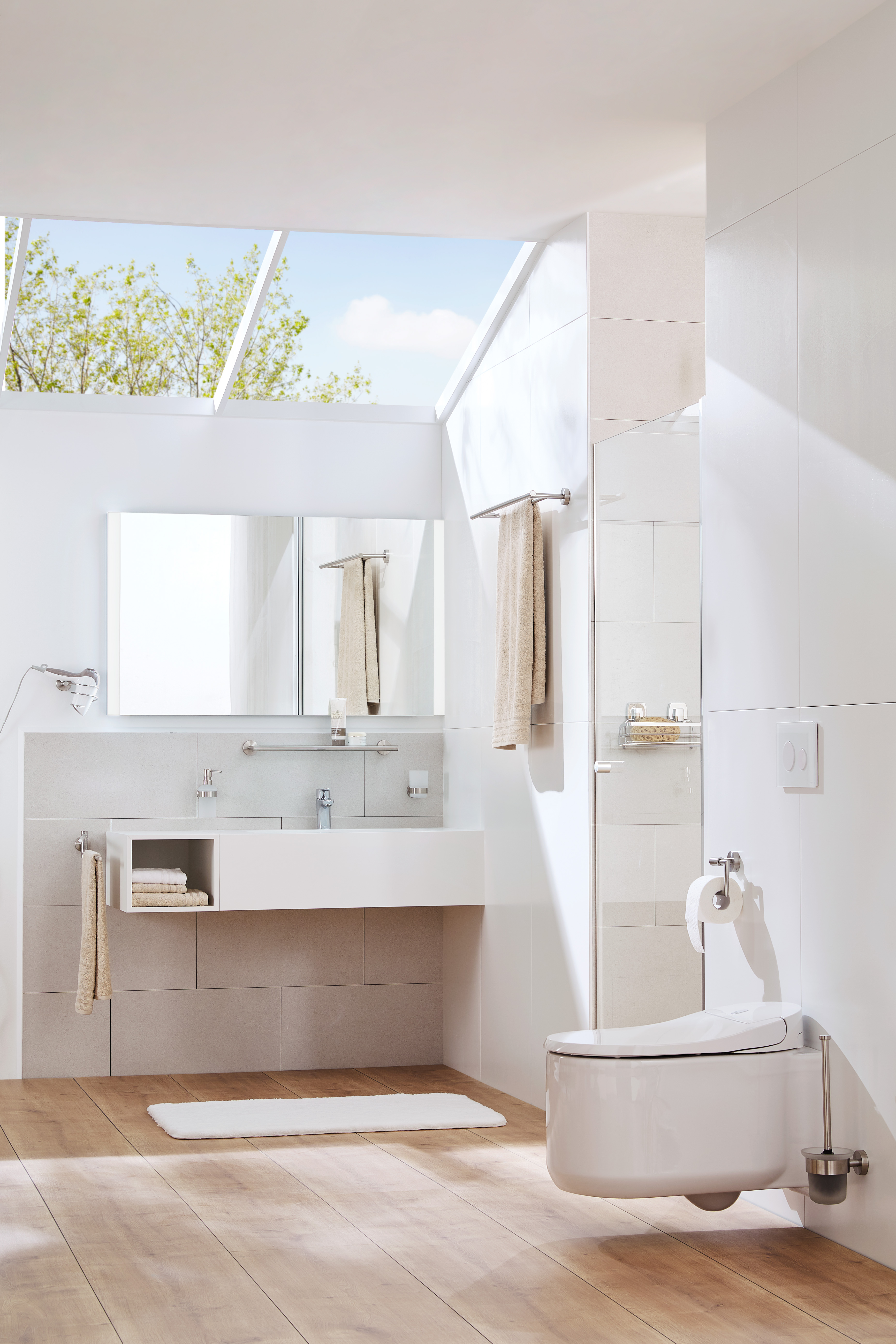 Modernes Badezimmer mit großem Fenster, weißer Einrichtung, Holzfußboden, Wandspiegel, Handtüchern und WC.