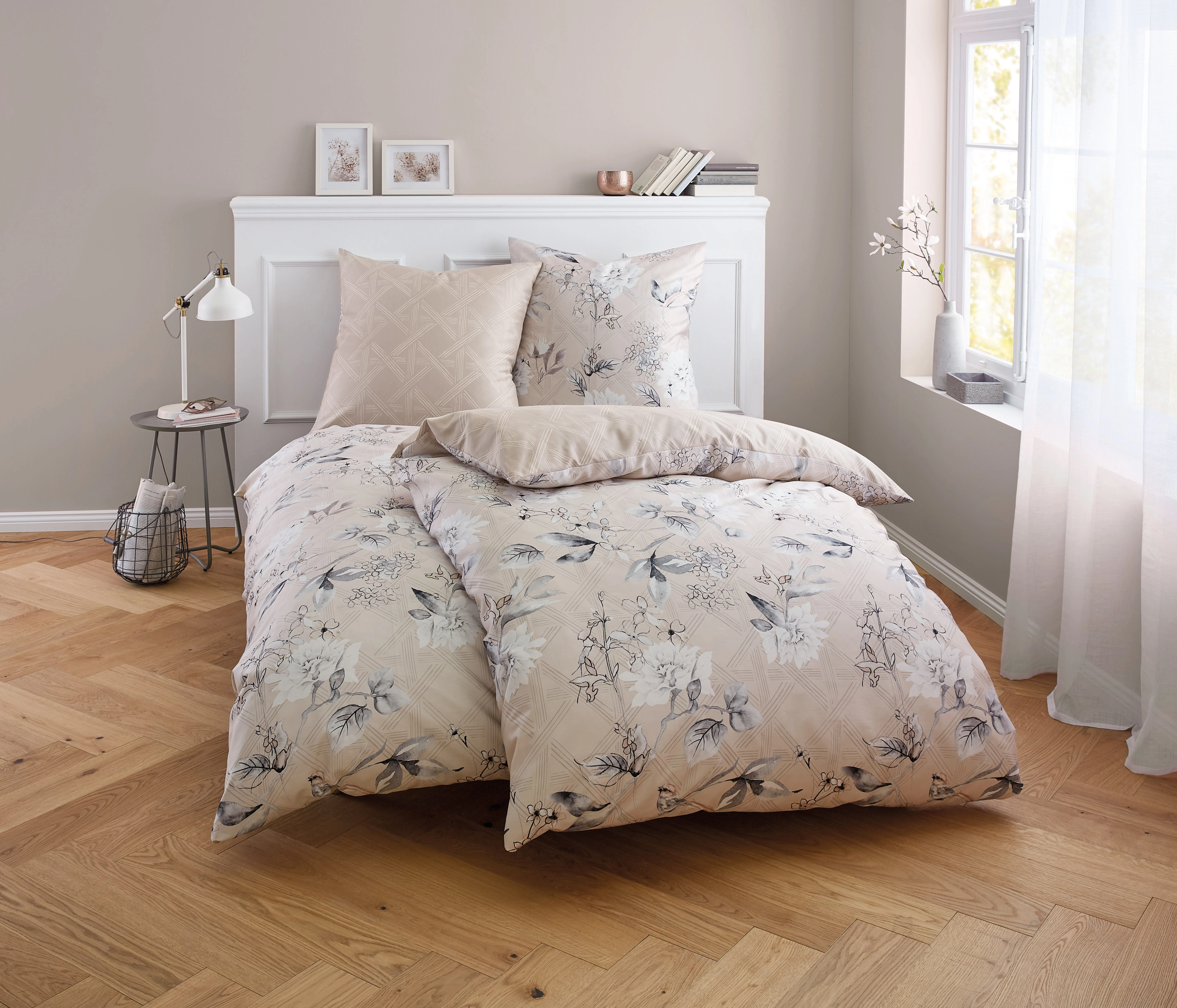 Bettwäsche-Set in Beige mit floralem Muster, dekoriert in einem gemütlichen Schlafzimmer mit Holzboden und natürlichem Licht.