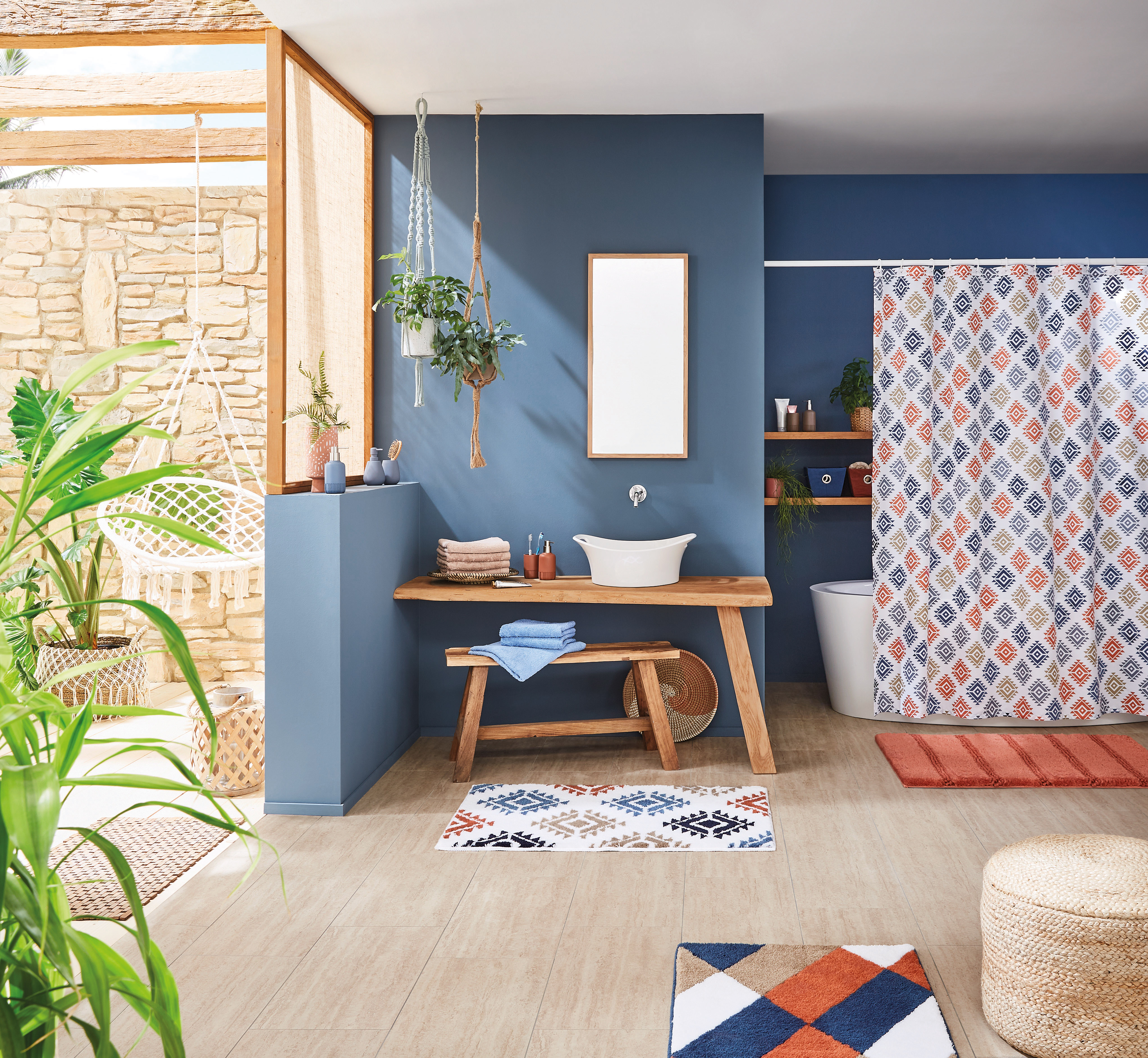 Modernes Badezimmer mit blauen Wänden, Holzdetails, Pflanzen und farbenfrohem Duschvorhang im geometrischen Muster.