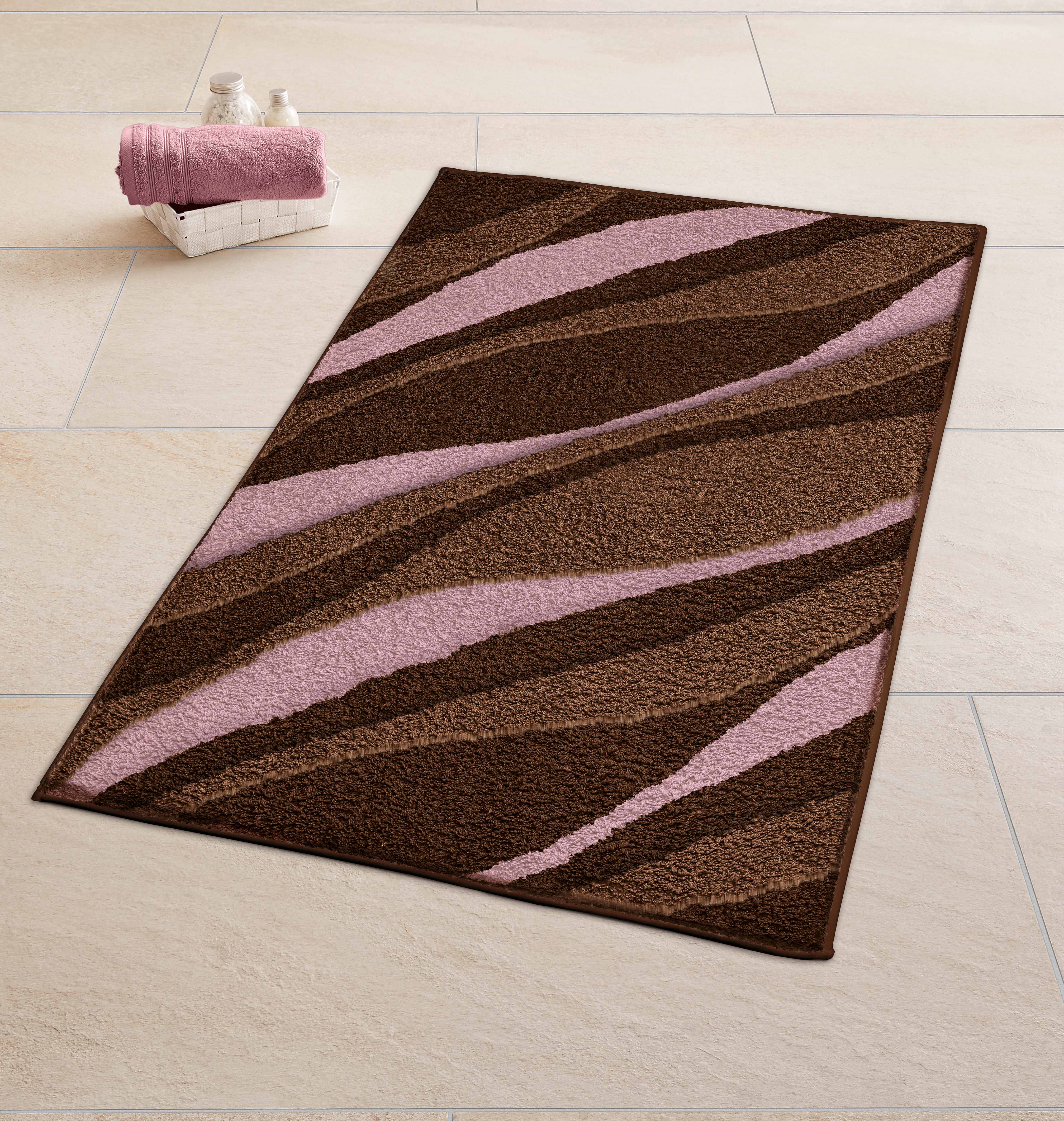 Badematte mit wellenförmigem Muster in Braun- und Rosatönen auf hellen Fliesen. Ideal für ein stilvolles Badezimmer.