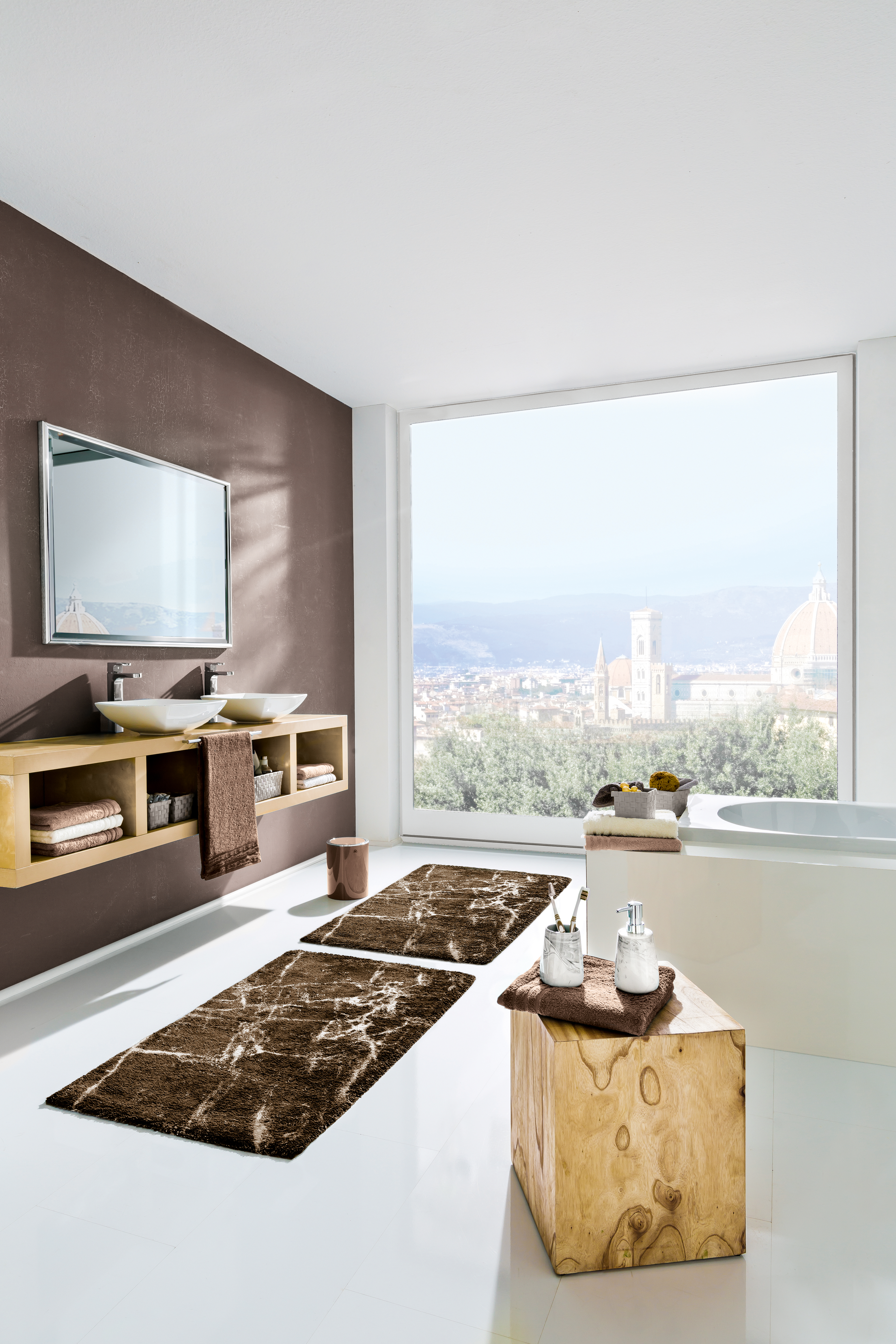 Modernes Badezimmer mit braunen Akzenten, großem Fenster mit Stadtblick, Doppelwaschbecken, Badewanne und stilvollen Teppichen.