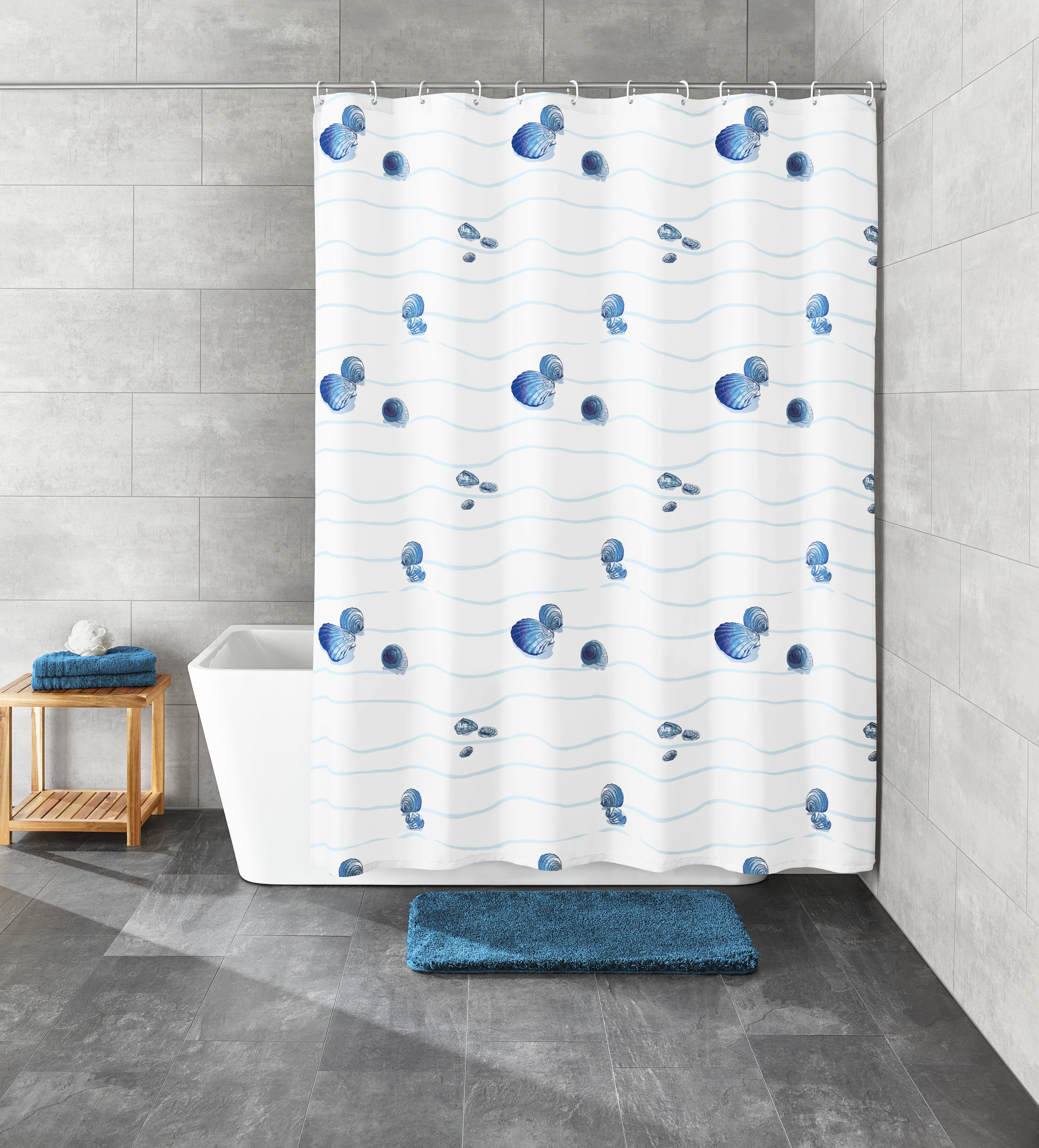Duschvorhang mit blauem Muschelmuster, passend zu blauen Badteppichen, in modernem Badezimmer mit grauen Fliesen.