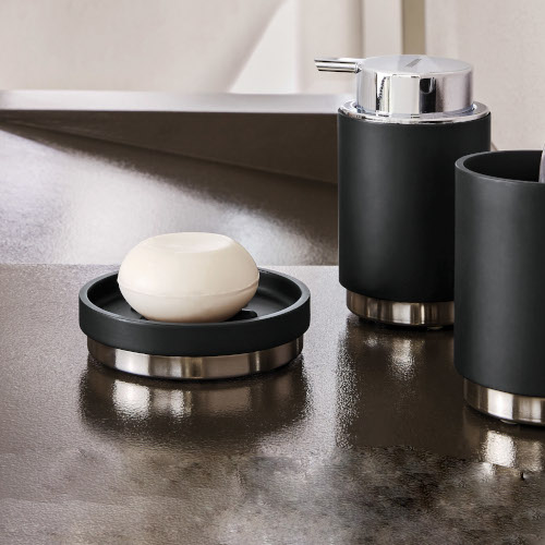 Elegantes Badezimmer-Set in Schwarz und Silber mit Seifenspender, Seifenschale und Zahnputzbecher auf glänzender Oberfläche.