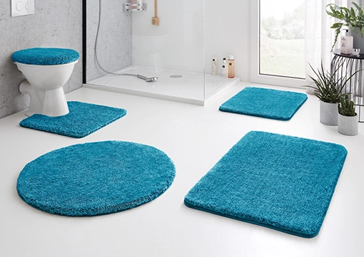 Türkisfarbene Badematten-Set in modernem Badezimmer, bestehend aus WC-Deckelbezug, Vorlegern und Duschmatte.
