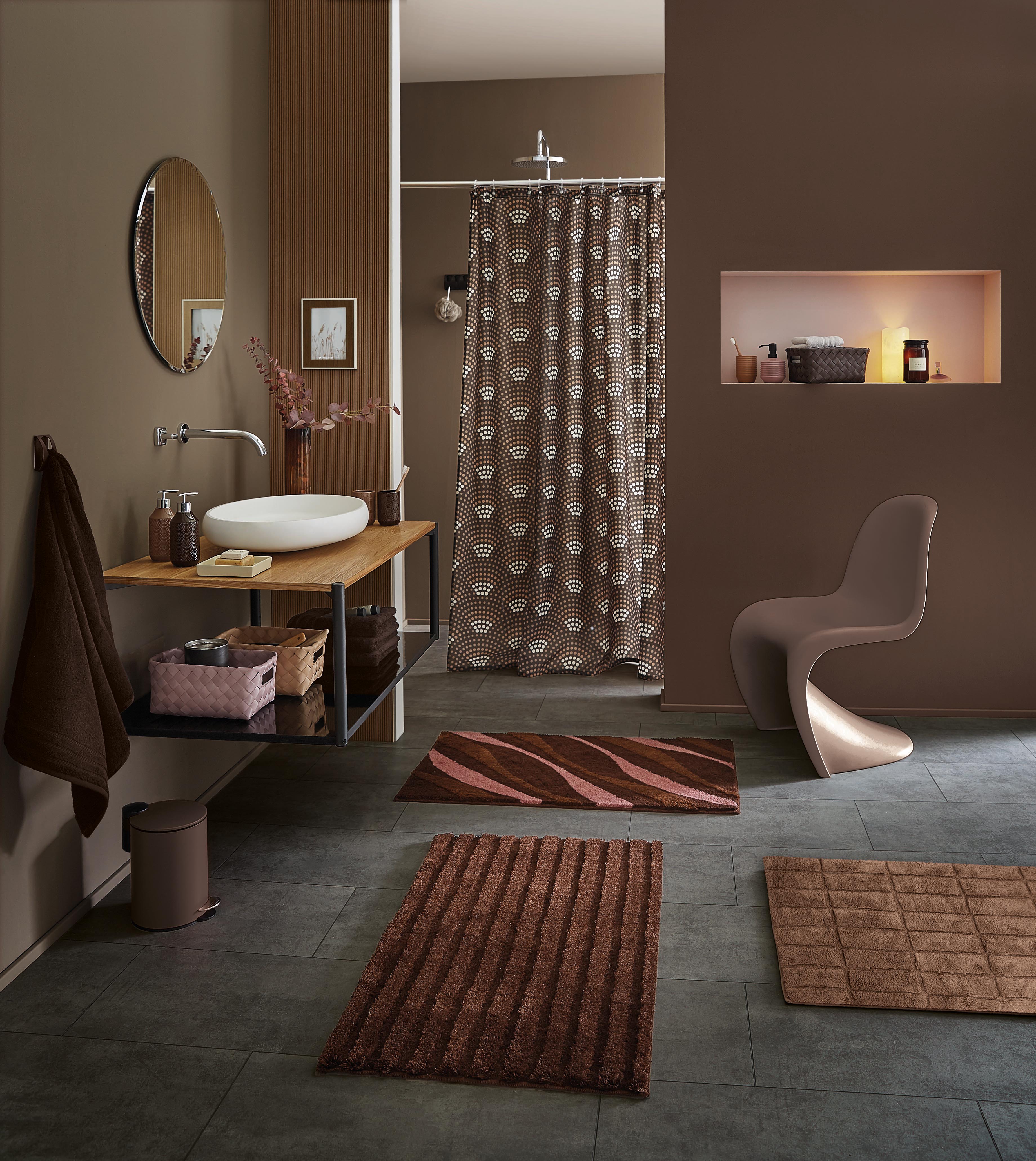 Modernes Badezimmer mit braunen Akzenten, stilvollen Teppichen und Duschvorhang mit geometrischem Muster.