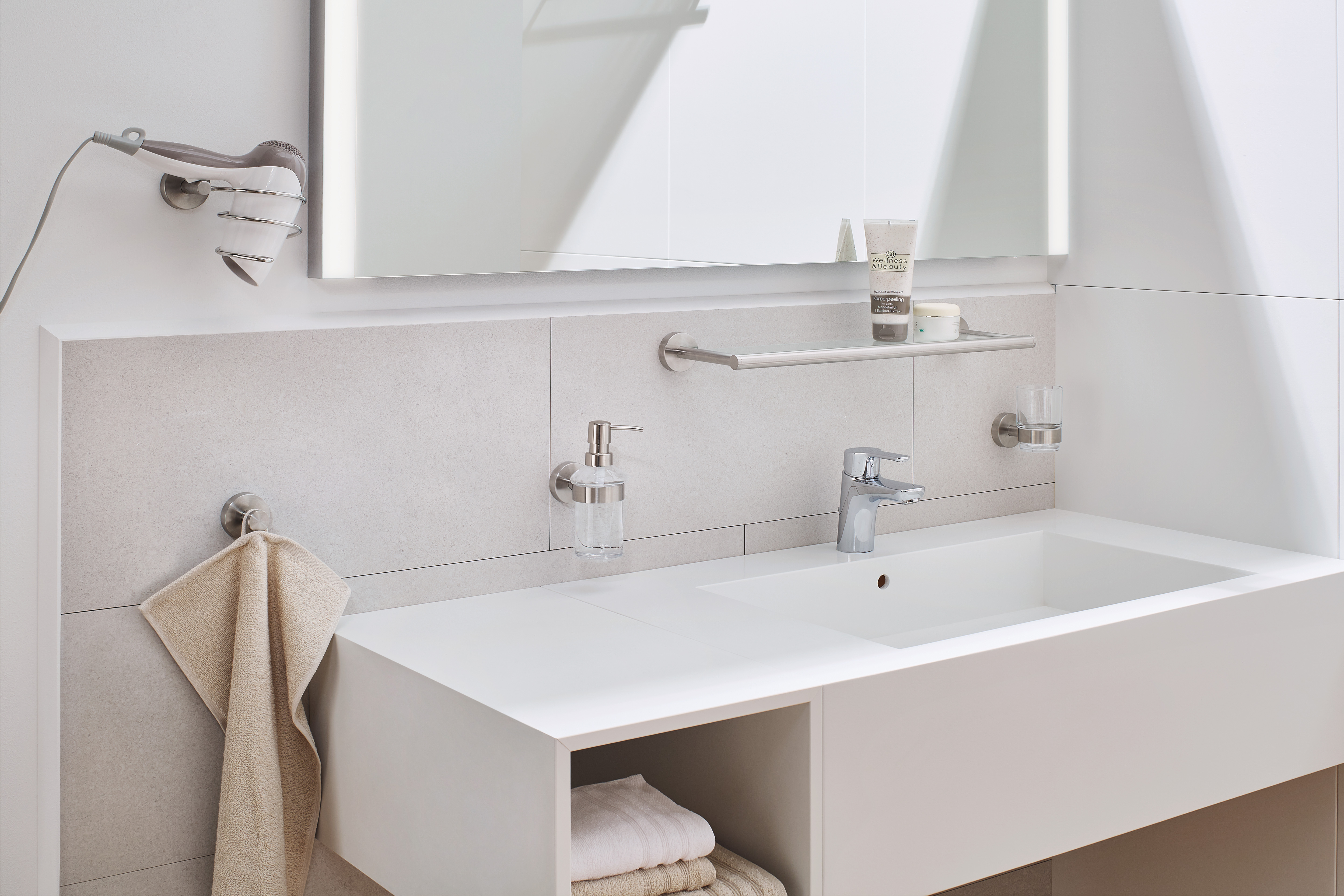 Modernes Badezimmer mit weißem Waschbecken, Handtuchhalter, Seifenspender und Spiegel. Minimalistisches Design mit hellen Farben.
