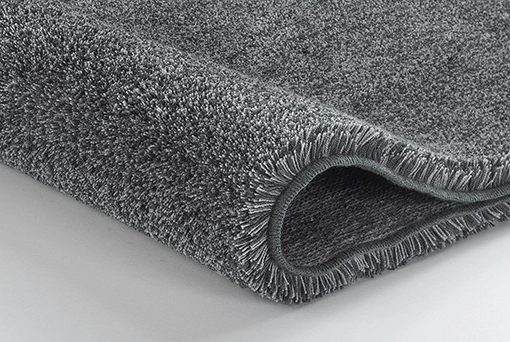 Grauer, flauschiger Teppich mit weicher Textur, ideal für Badezimmer oder Wohnräume.