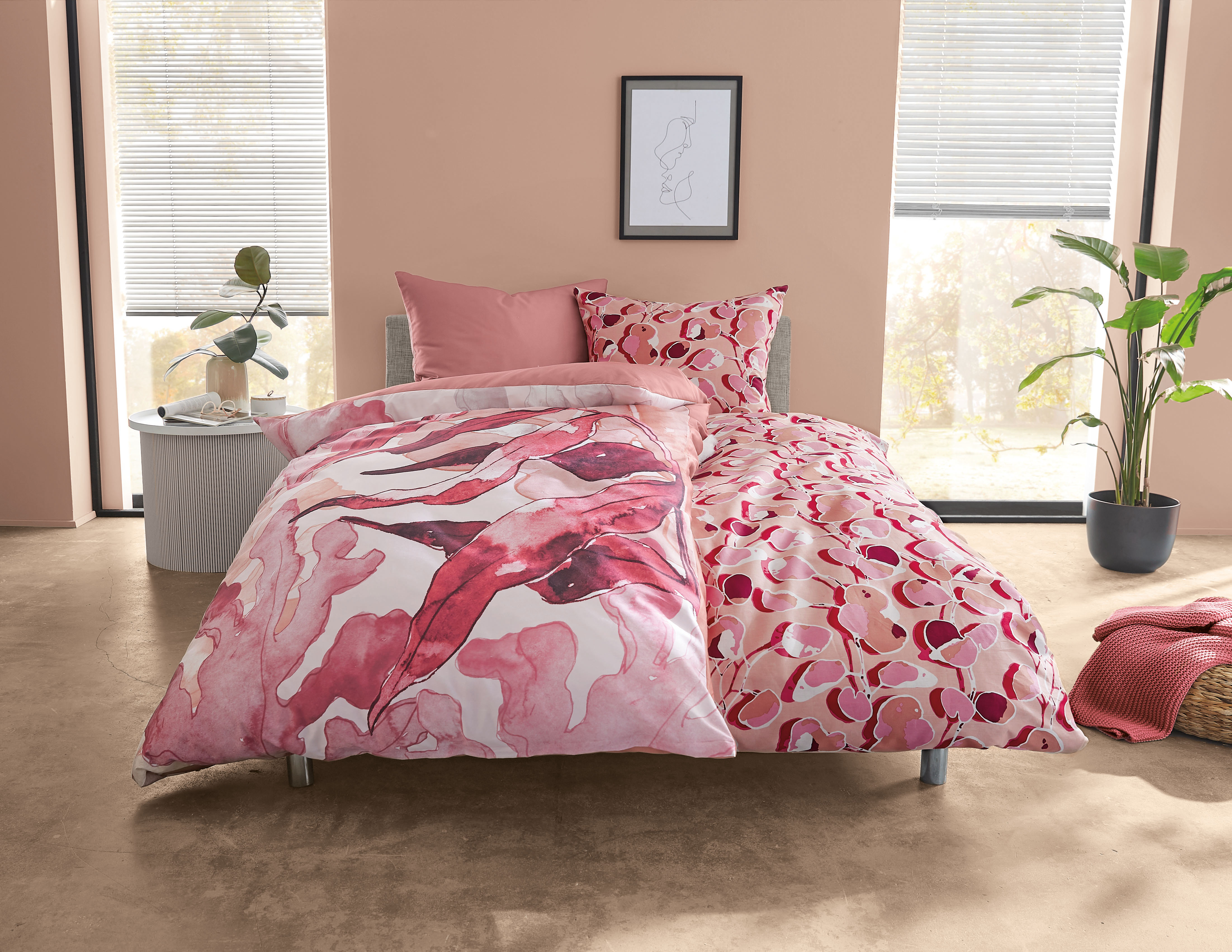 Bettwäsche-Set mit abstraktem, rosa-rot gemustertem Design in modernem Schlafzimmer mit Pflanzen und minimalistischer Dekoration.