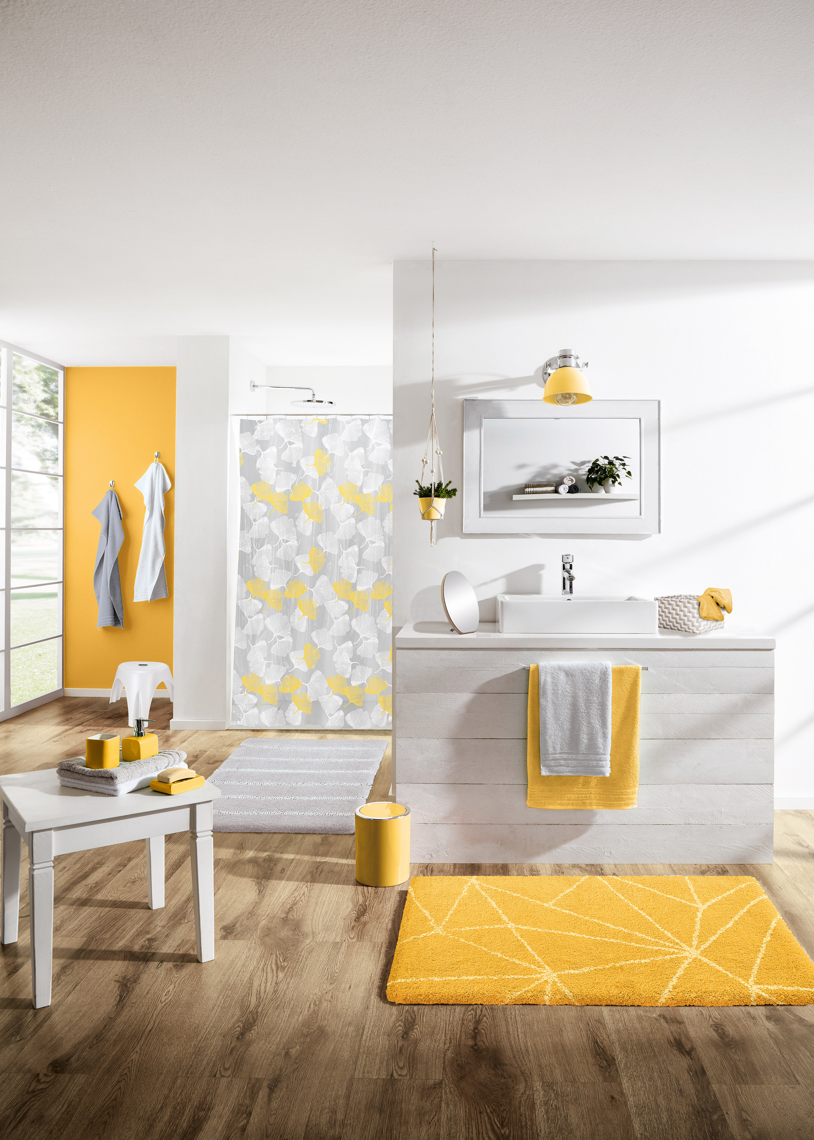 Modernes Badezimmer mit gelben und grauen Akzenten, Duschvorhang mit geometrischem Muster, gelber Teppich und Handtücher.