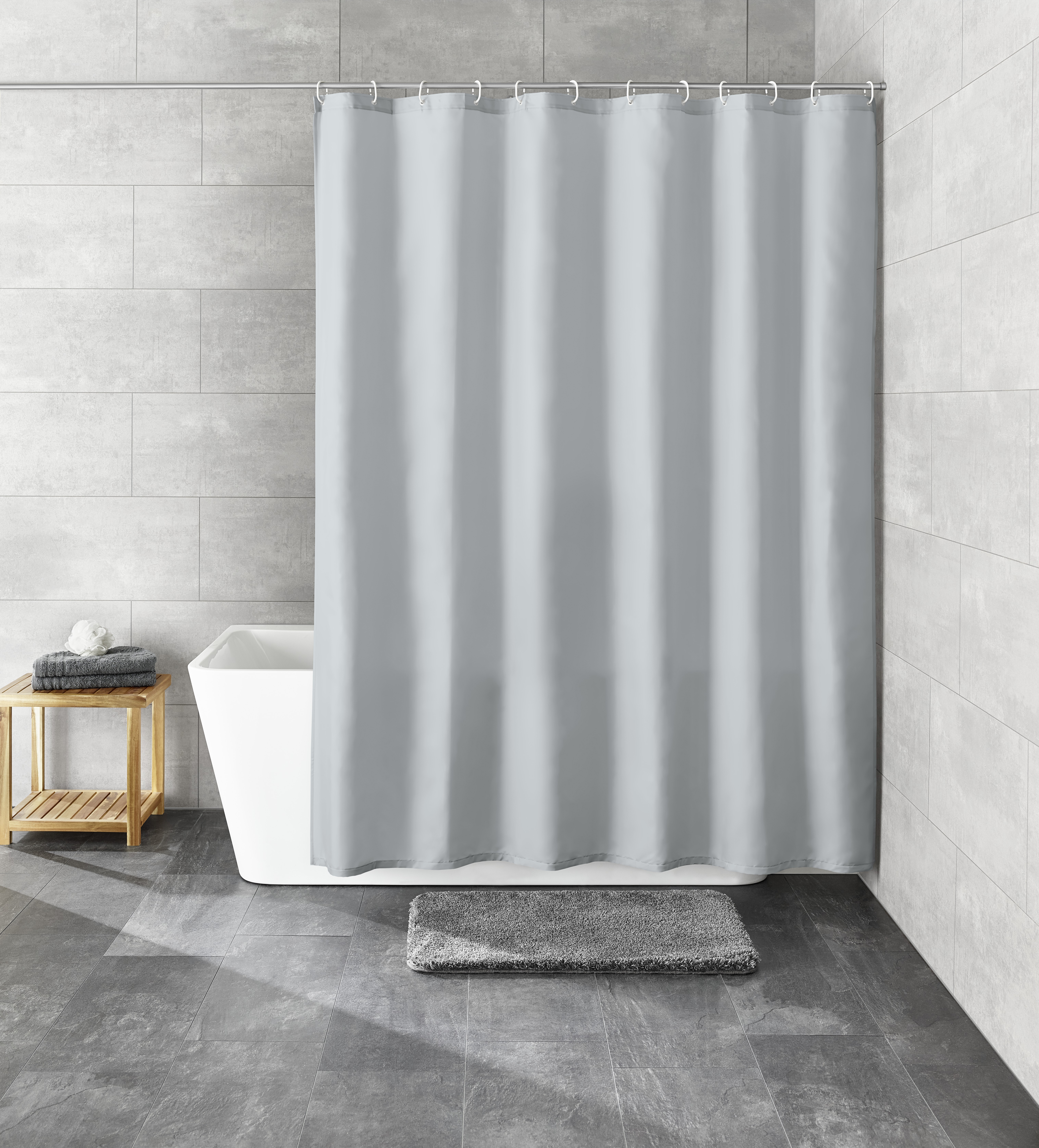 Grauer Duschvorhang in modernem Badezimmer mit grauen Fliesen, Badewanne, Holzregal und grauem Badteppich.