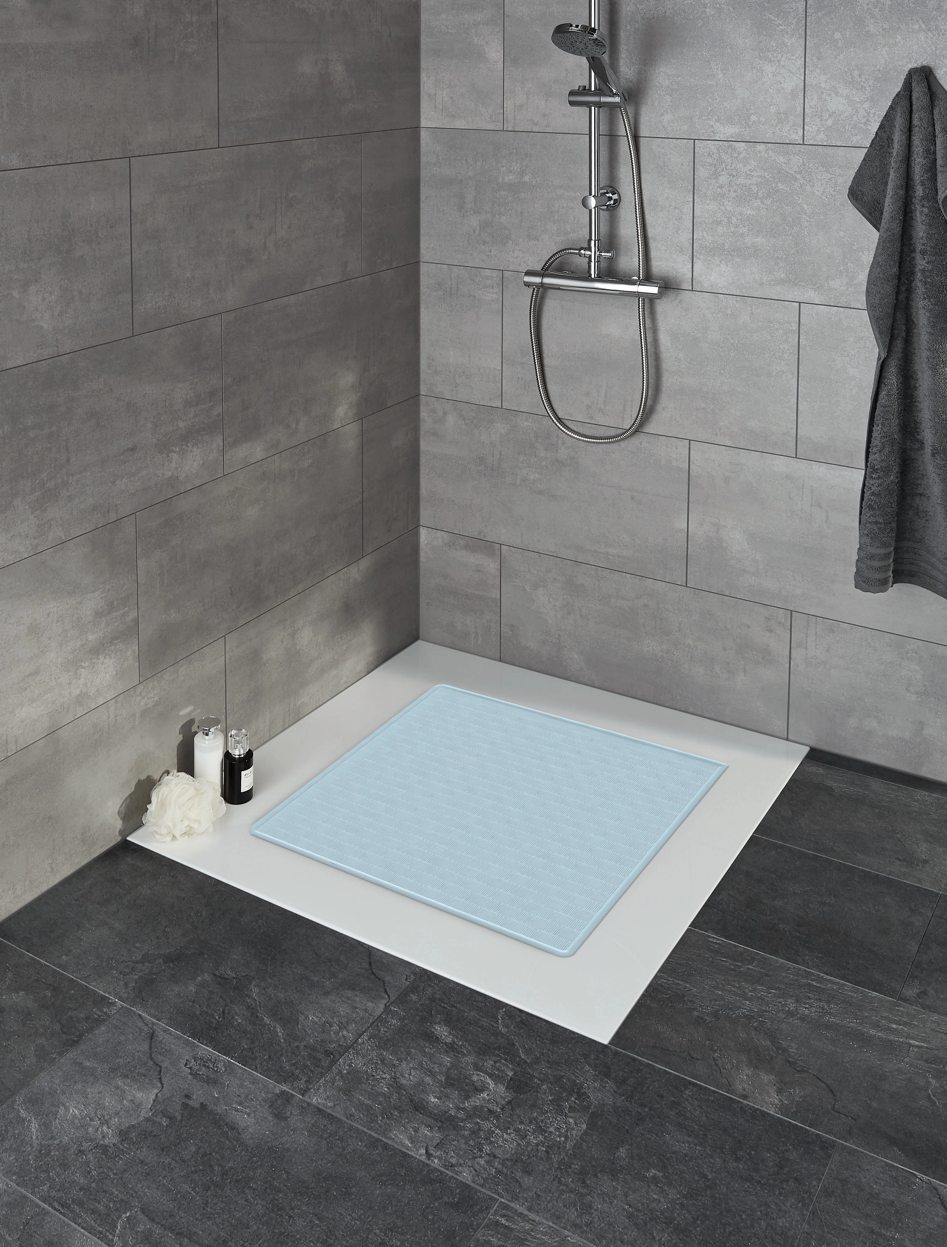 Rutschfeste Duschmatte in Hellblau, platziert in einer modernen grauen Dusche mit Fliesenwänden und -boden.