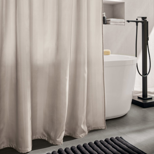 Beigefarbener Duschvorhang in modernem Badezimmer mit freistehender Badewanne und schwarzer Armatur.