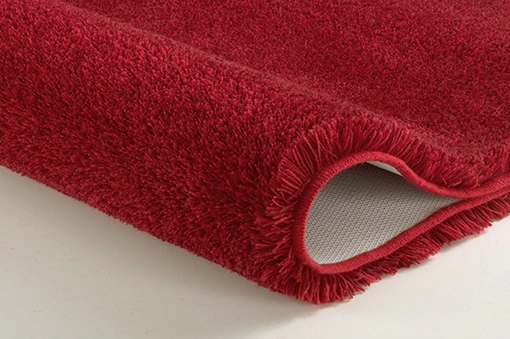 Roter, flauschiger Badteppich mit rutschfester Unterseite, ideal für ein gemütliches und sicheres Badezimmer.