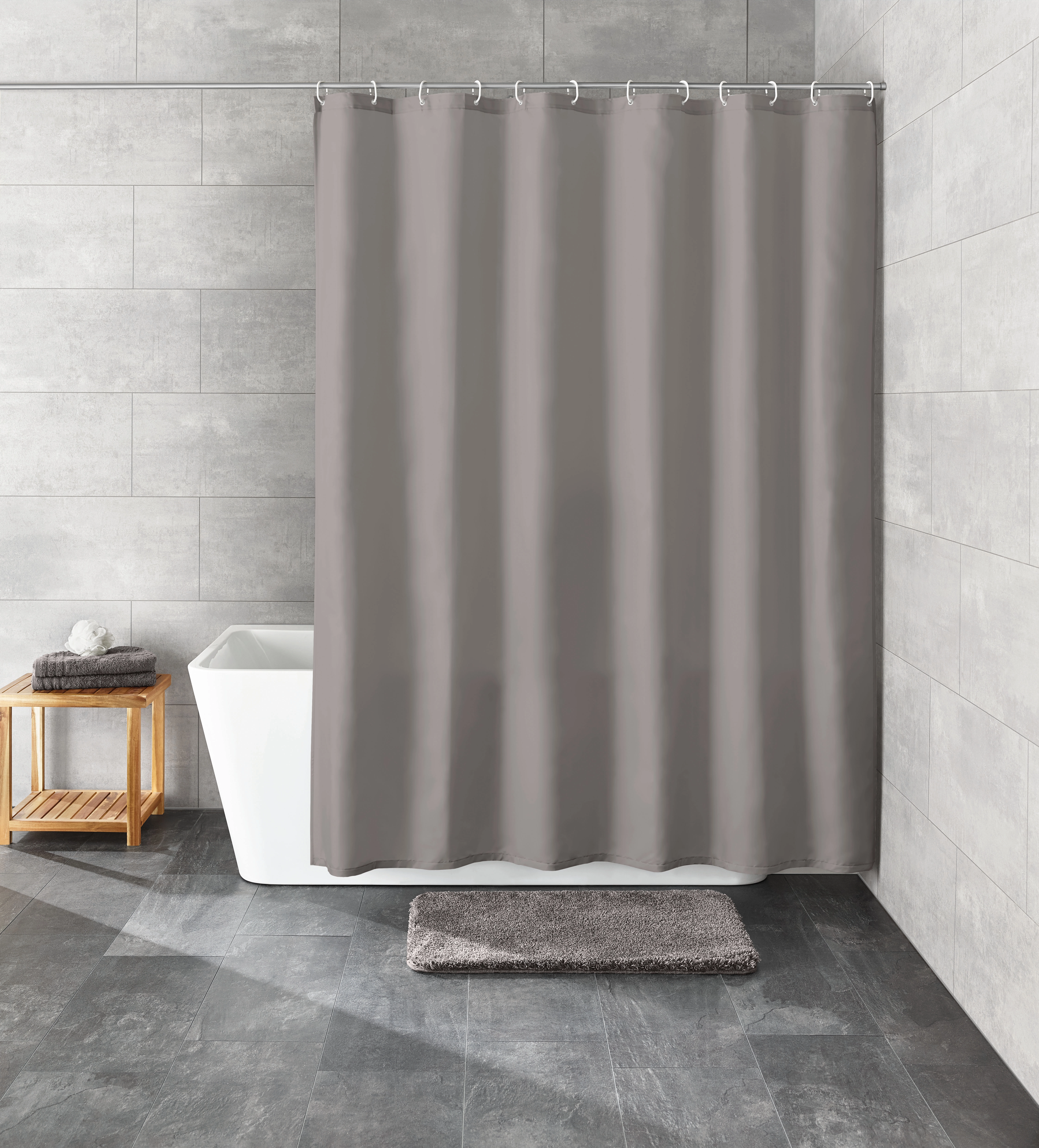 Grauer Duschvorhang in modernem Badezimmer mit grauen Fliesen, Badewanne, Holzregal und grauem Badteppich.