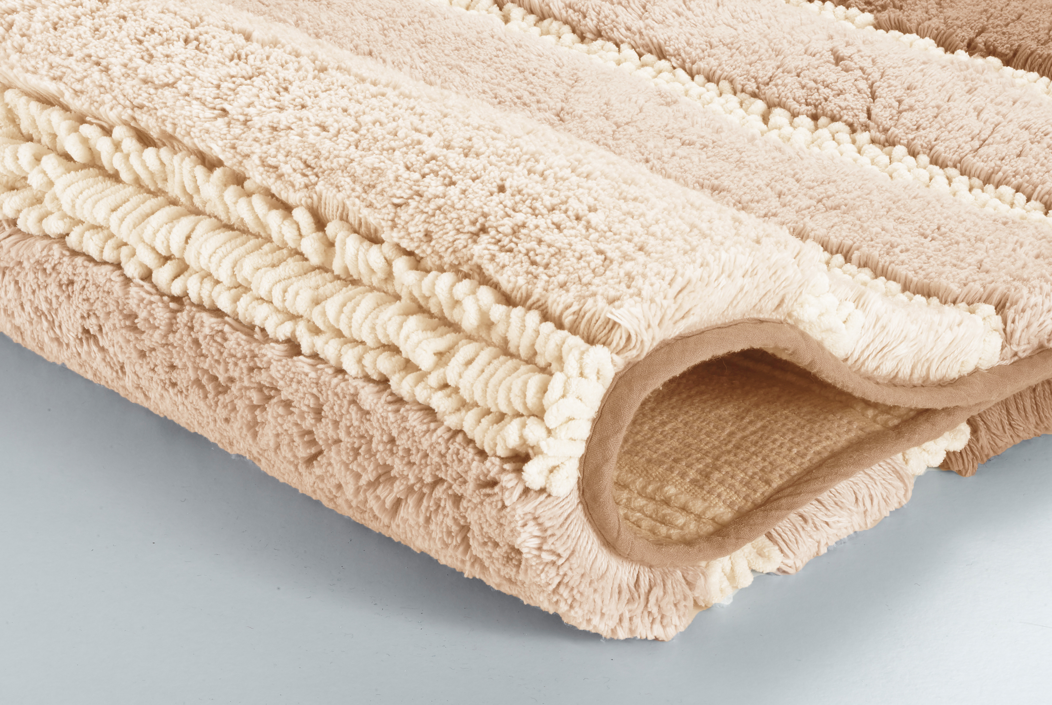 Weicher, beiger Badteppich mit strukturiertem Design und rutschfester Unterseite, ideal für ein gemütliches Badezimmer.