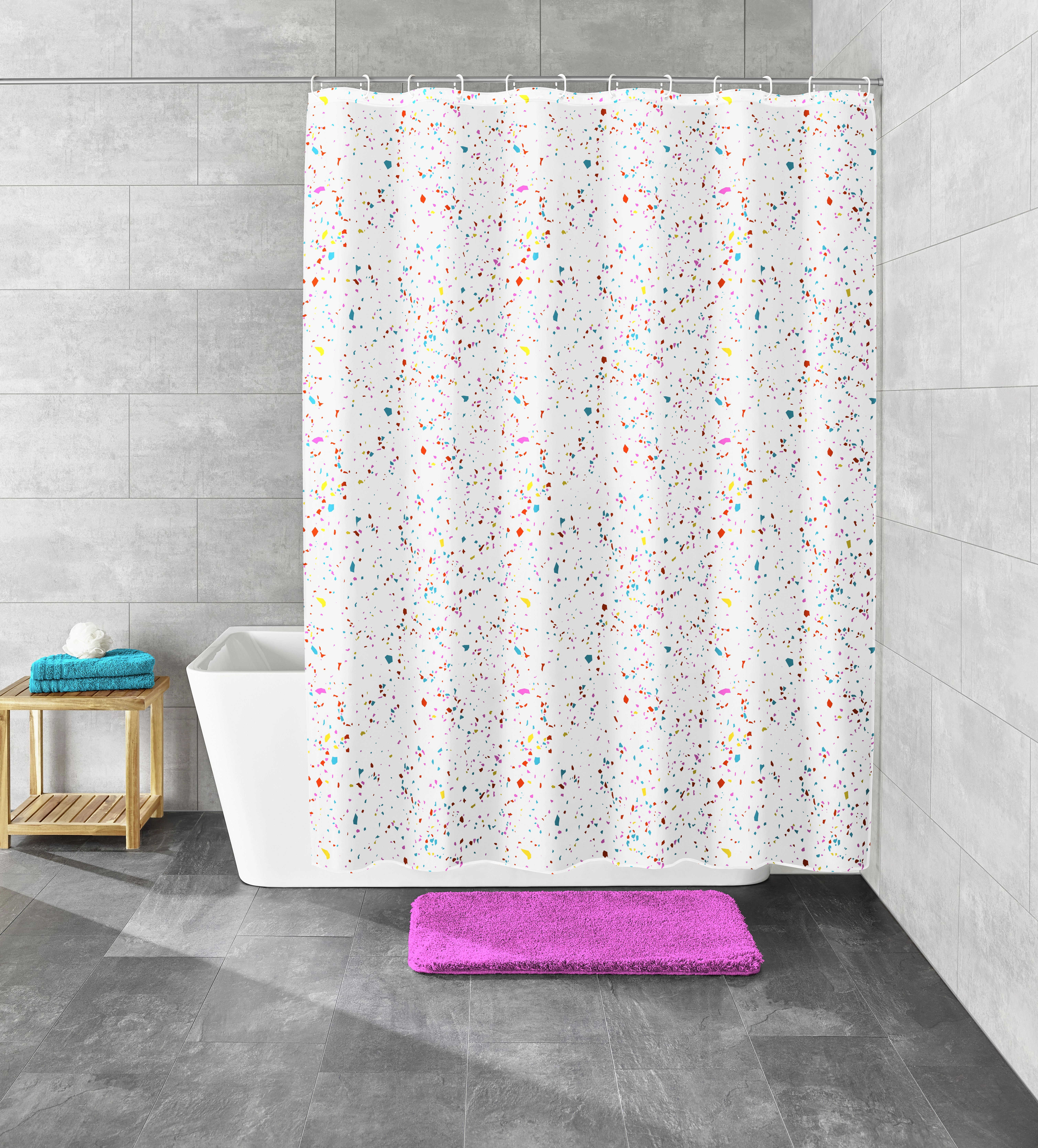 Duschvorhang mit buntem Konfetti-Muster, moderne graue Fliesen, weiße Badewanne, lila Badematte, Holzregal mit Handtüchern.