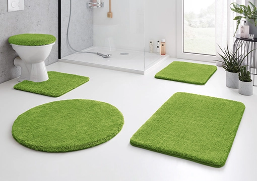 Grünes Badezimmer-Set mit WC-Deckelbezug, Duschvorleger und Teppichen, passend für moderne, helle Badezimmer.