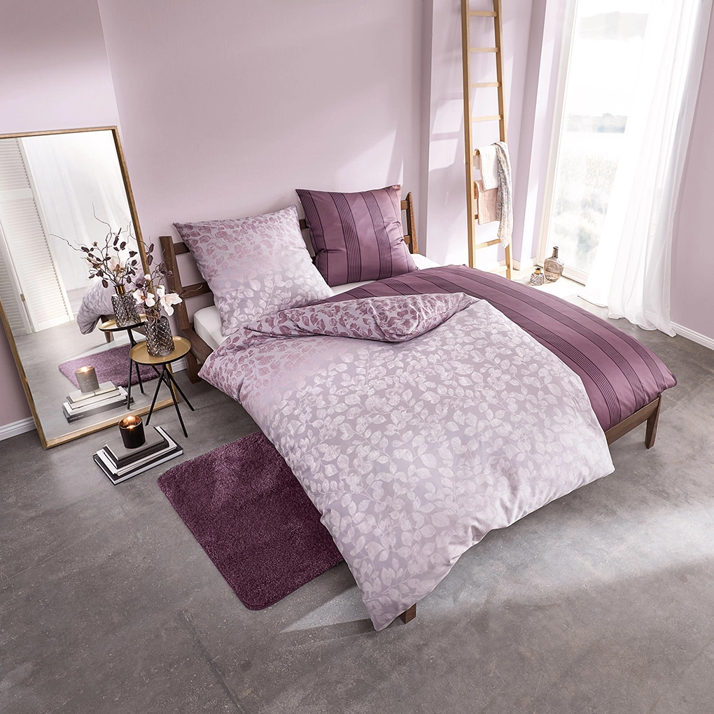 Bettwäsche-Set in zarten Lila- und Rosatönen mit floralem Muster, dekoriert in einem modernen Schlafzimmer.