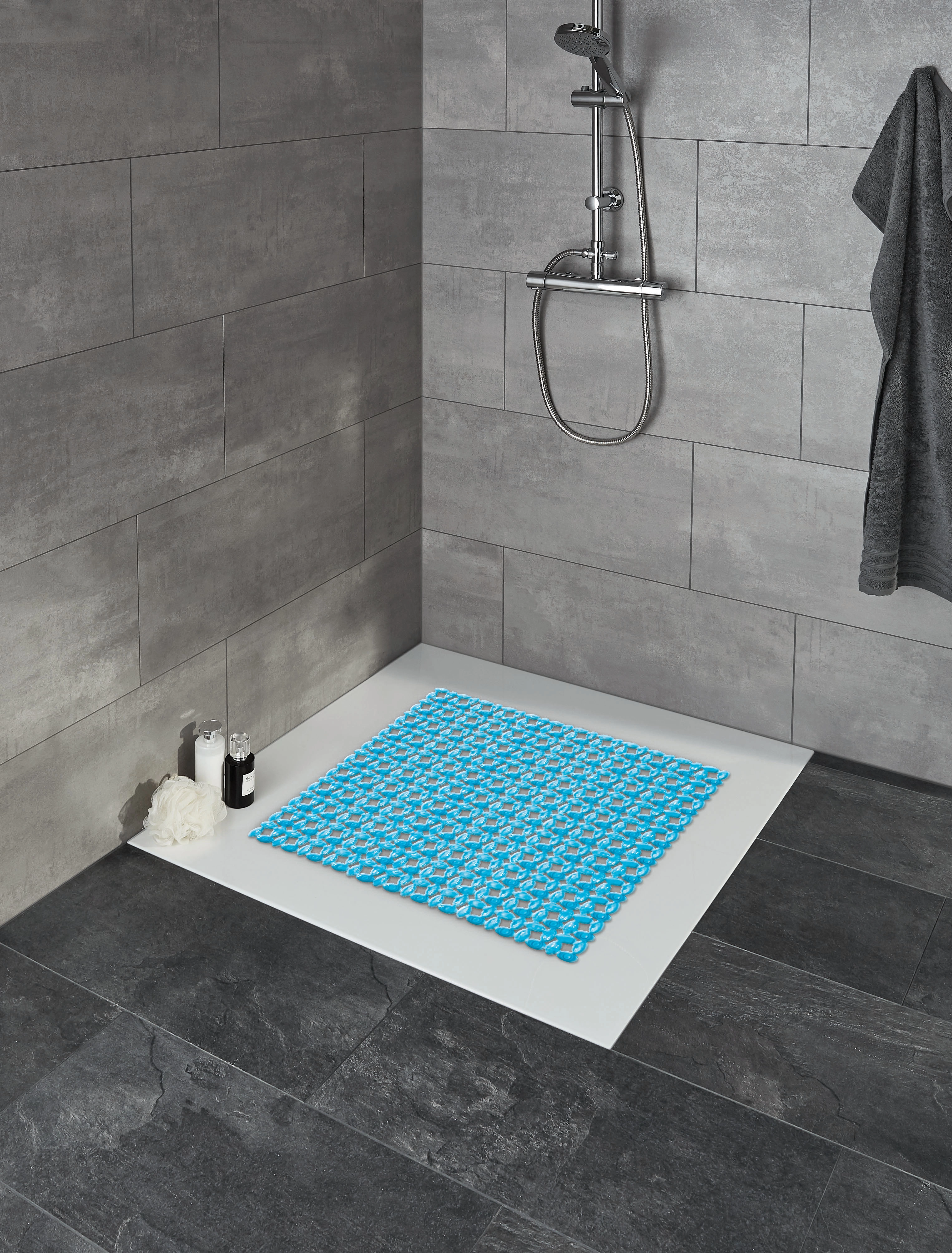 Blaue Duschmatte mit modernem Muster in einer stilvollen, grauen Fliesendusche.