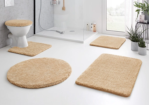 Beige Badematte-Set in modernem Badezimmer mit Dusche, WC und Pflanzen. Weiche, flauschige Textur für Komfort und Stil.