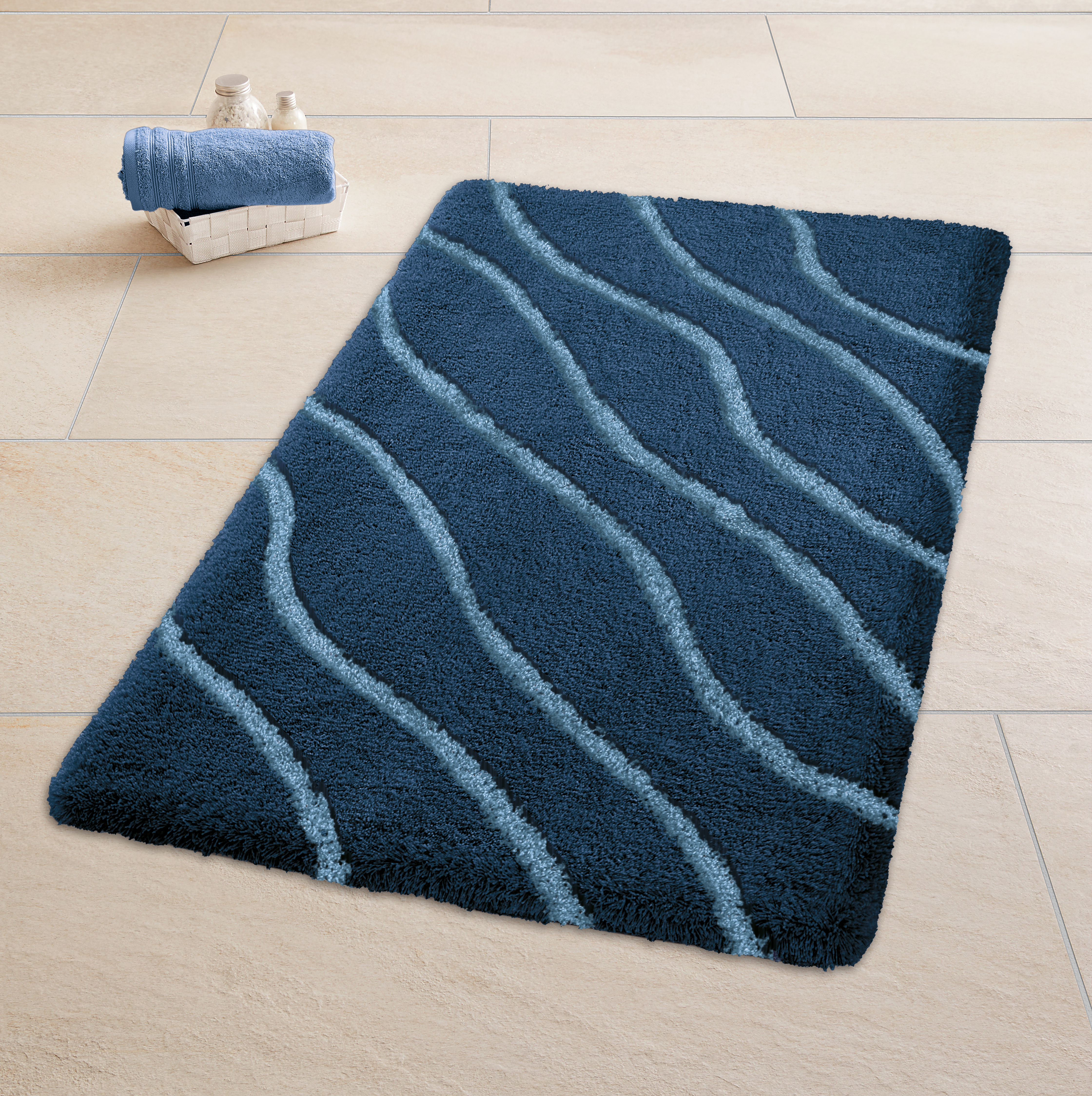 Weicher, dunkelblauer Badteppich mit wellenförmigem Muster, dekoriert mit einem weißen Korb und blauen Handtüchern.