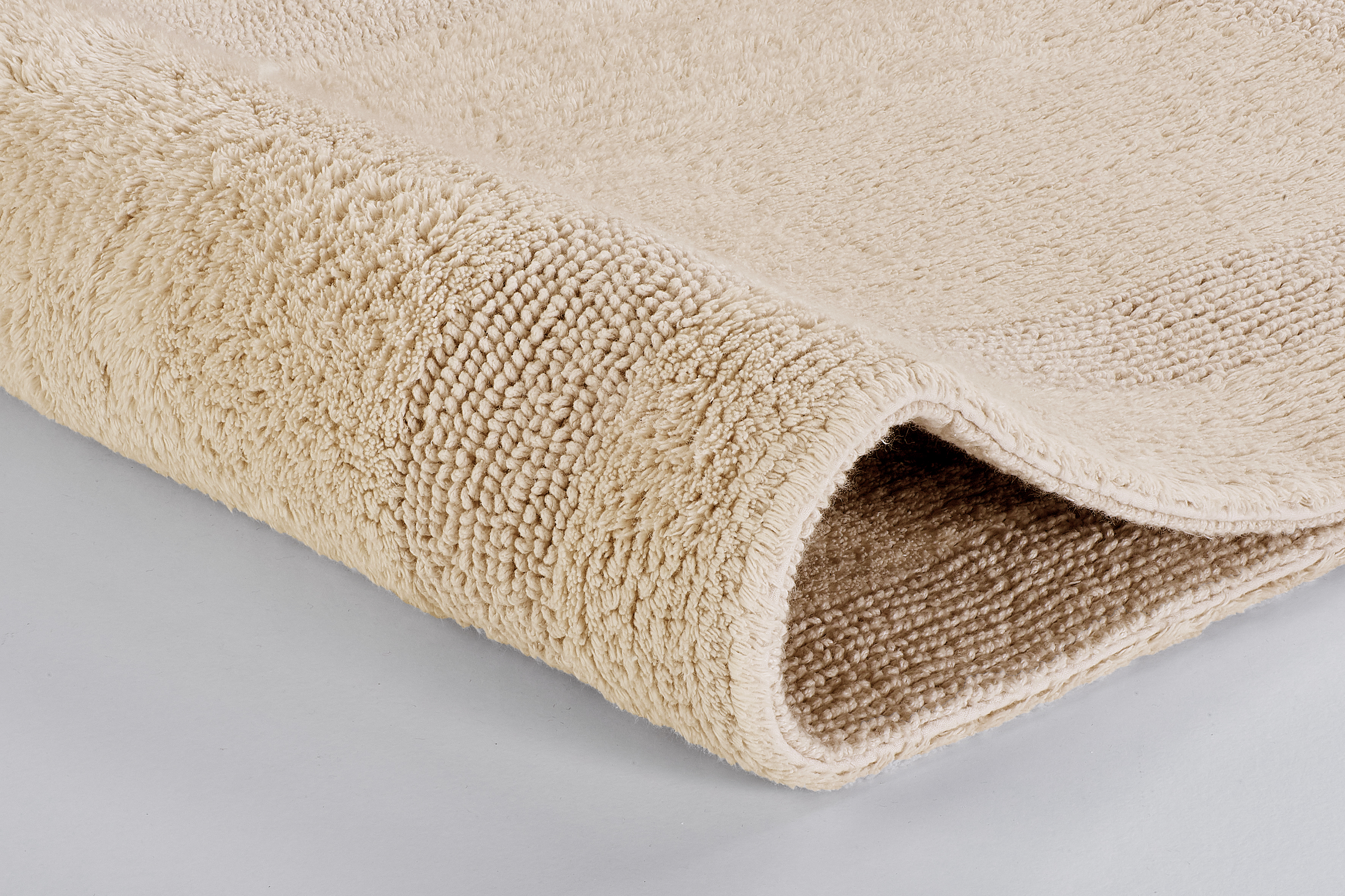 Weicher, beiger Badteppich mit dichter, flauschiger Struktur, ideal für ein gemütliches Badezimmerambiente.