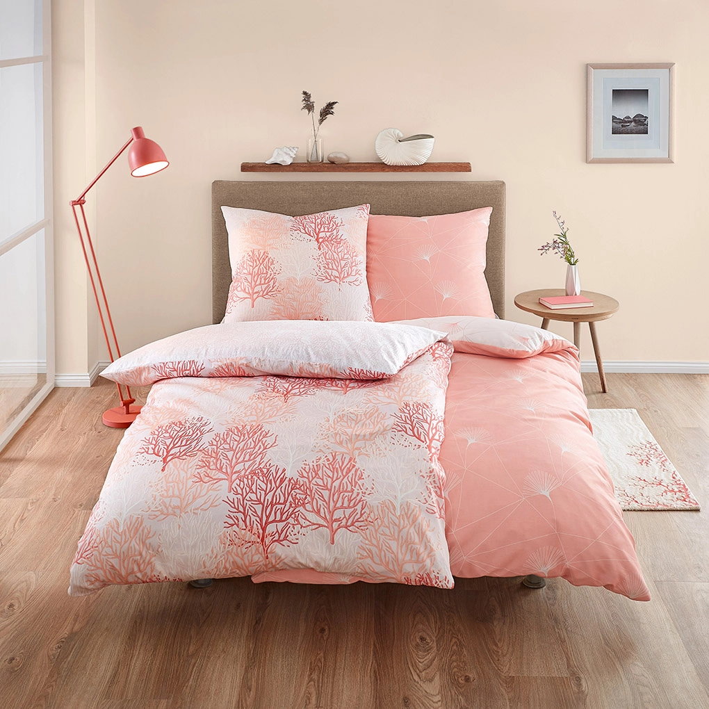 Bettwäsche-Set in zarten Rosa- und Weißtönen mit Korallenmuster, dekoriert mit passendem Kissen und Nachttisch.