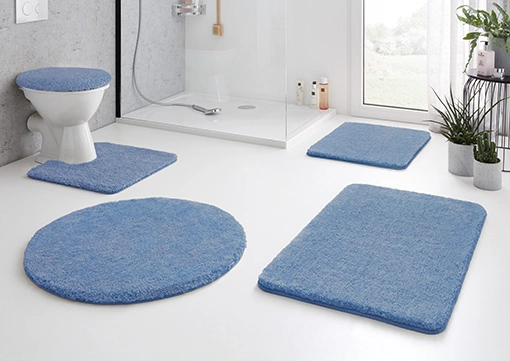 Blaue Badematte-Set in modernem Badezimmer mit Dusche, WC und Pflanzen. Weiche Textur, rutschfest und stilvoll.
