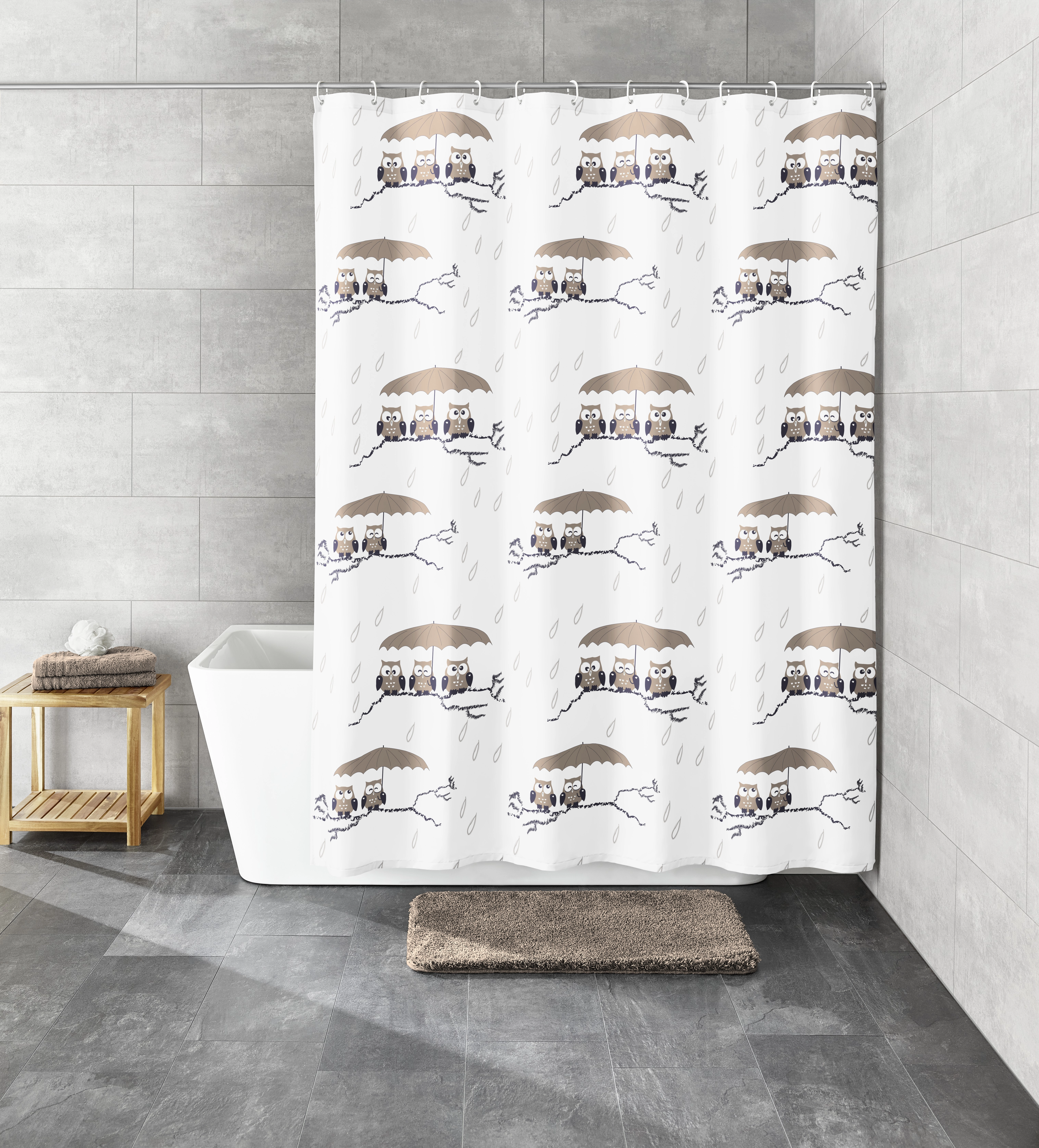 Duschvorhang mit Eulenmotiv, graue Fliesen, weiße Badewanne, Holzregal mit Handtüchern, grauer Teppich.